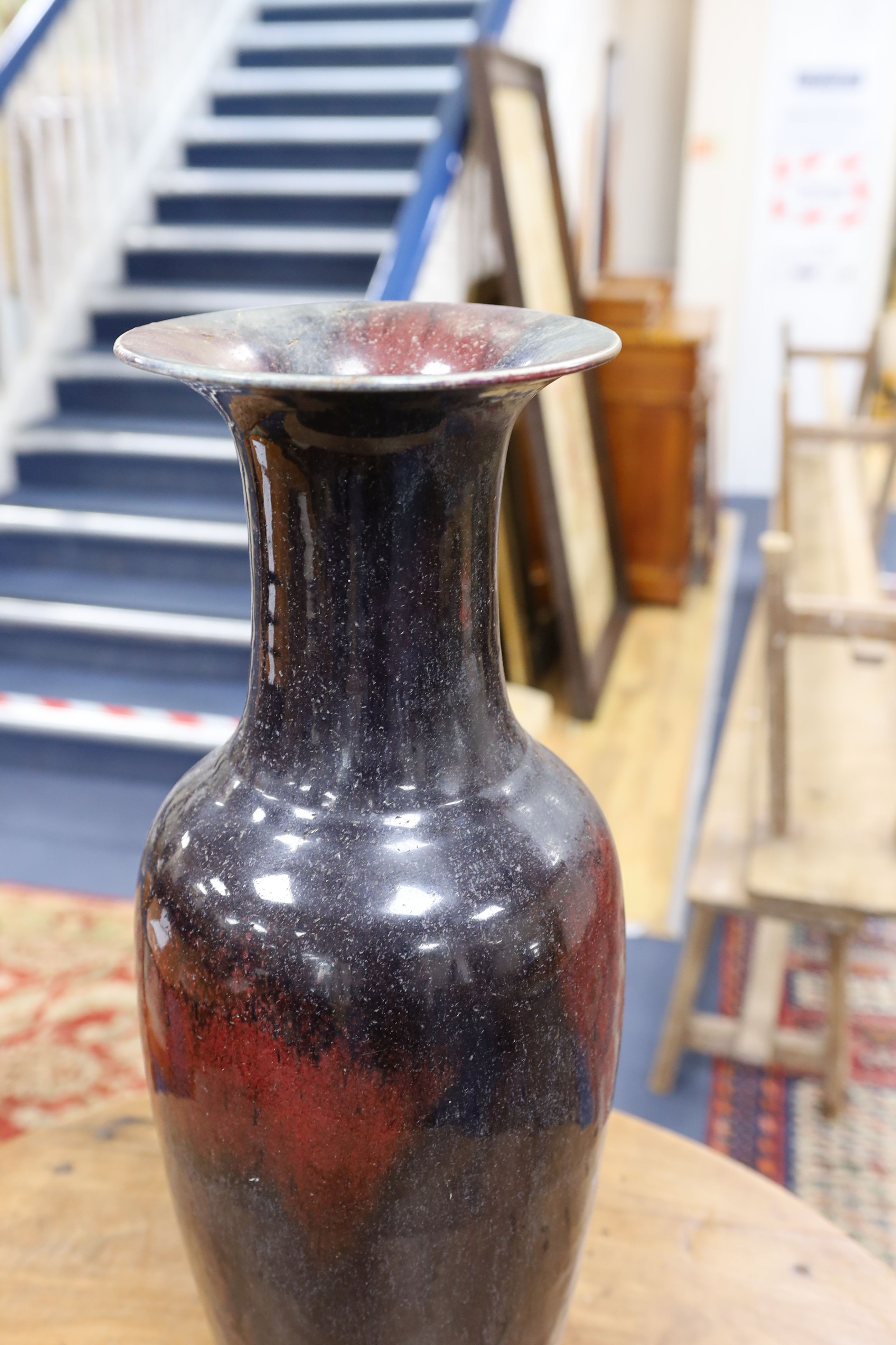 A large Chinese sang de boeuf glazed vase on carved wooden stand., Vase 61 cms high not including stand.